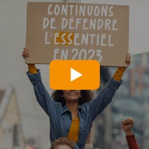 Photo d'une femme avec une pancarte "Continuons de défendre l'essentiel en 2023"
