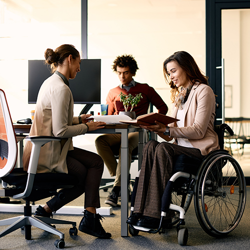 Photo de 3 personnes dans un bureau dont une femme en fauteuil roulant