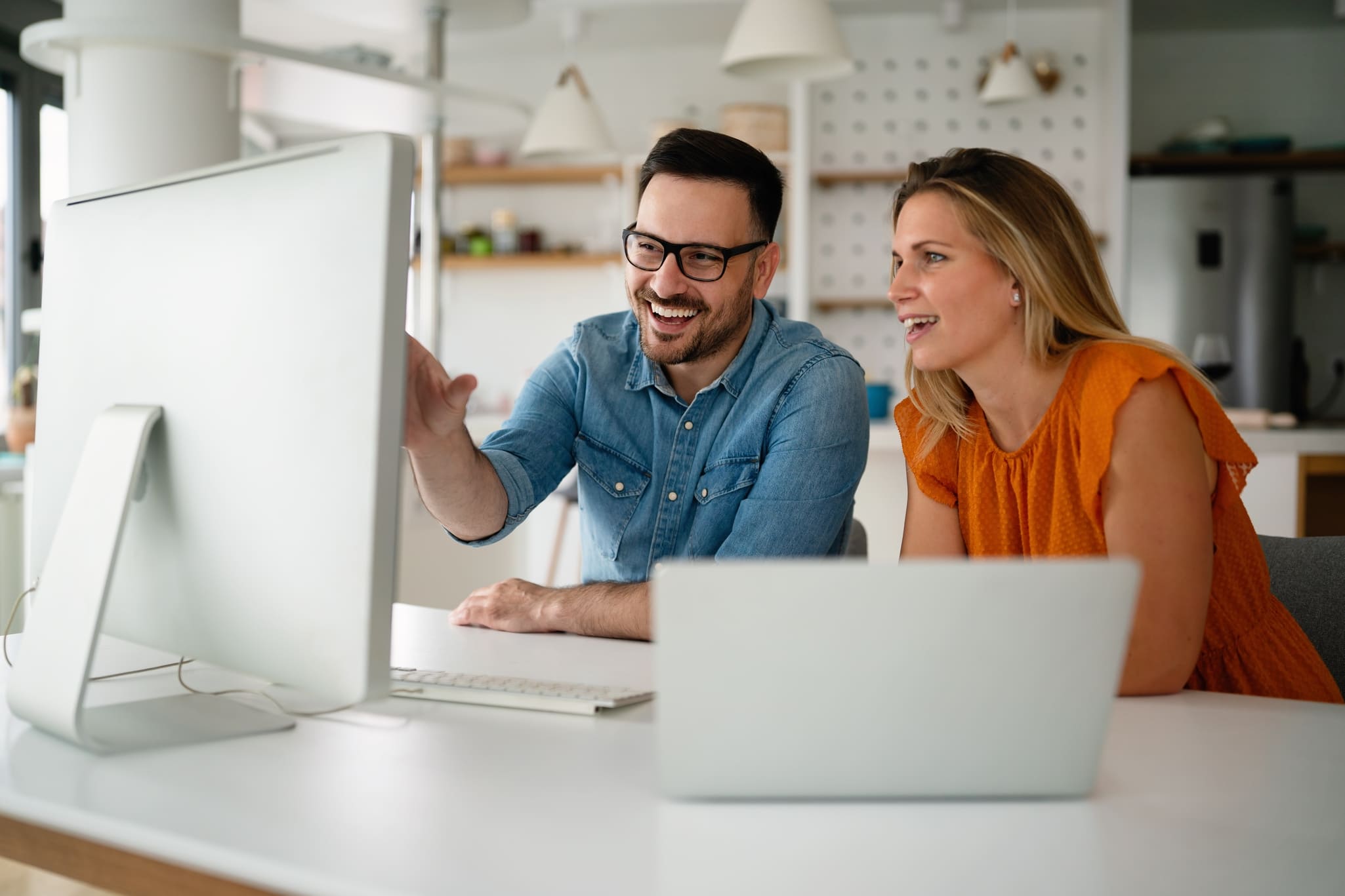 Photo de deux personnes souriantes regardent un écran d'ordinateur