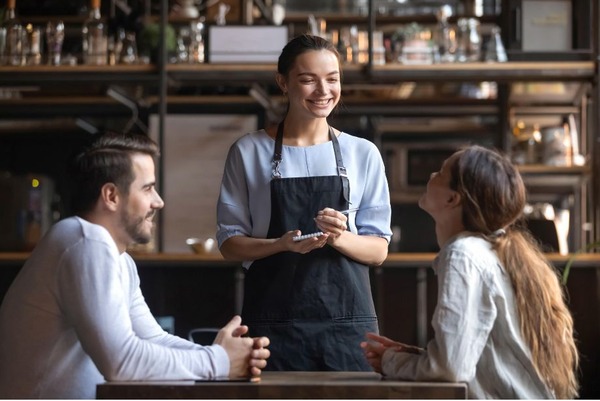 Photo de deux personnes à table d'un restaurant et une serveuse