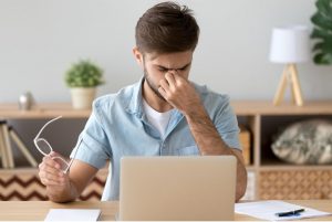 Photo d'un homme devant son écran d'ordinateur qui a mal à la tête