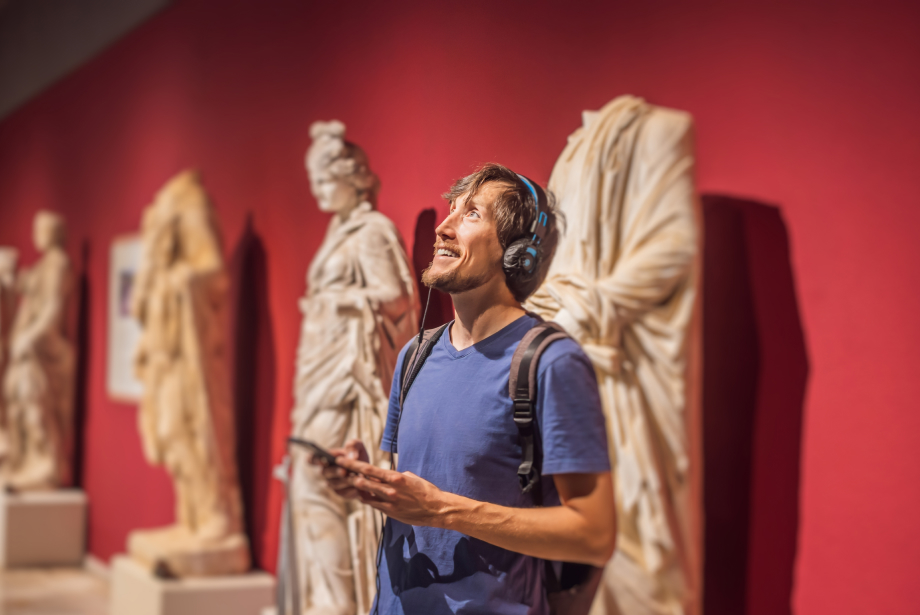 Homme portant un casque au musée souriant devant des statues