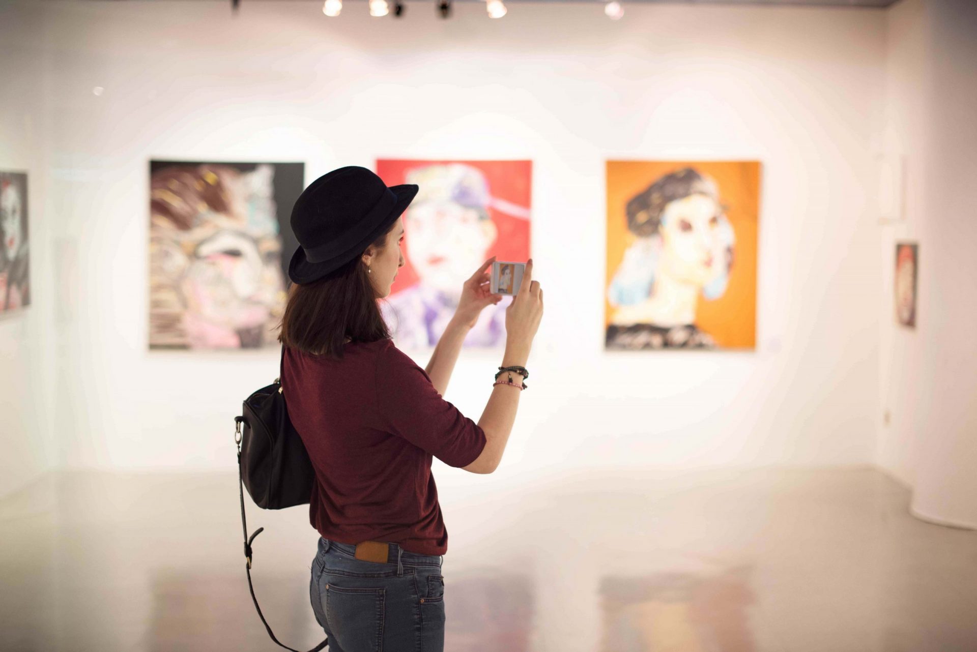 Jeune femme prend une photo d'un tableau dans un musée