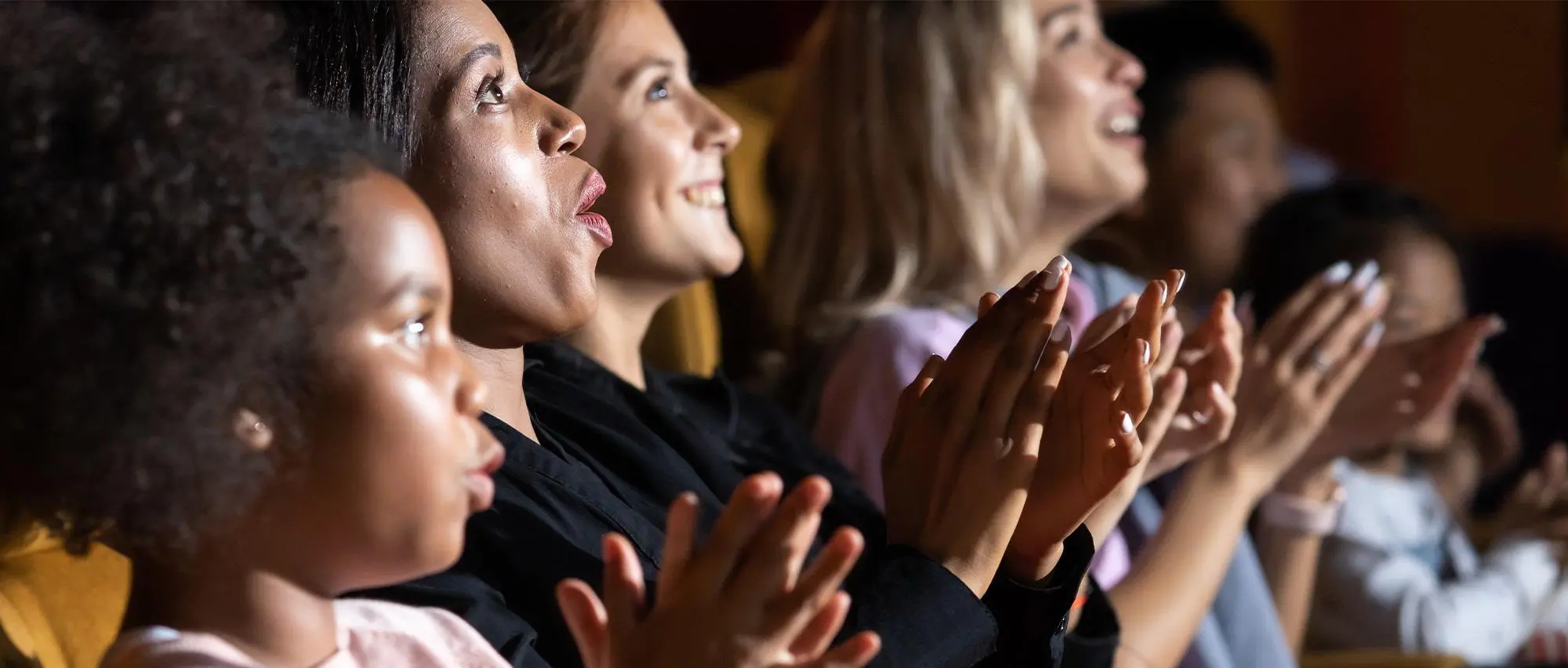 Quatre spectateurs applaudissent au théâtre